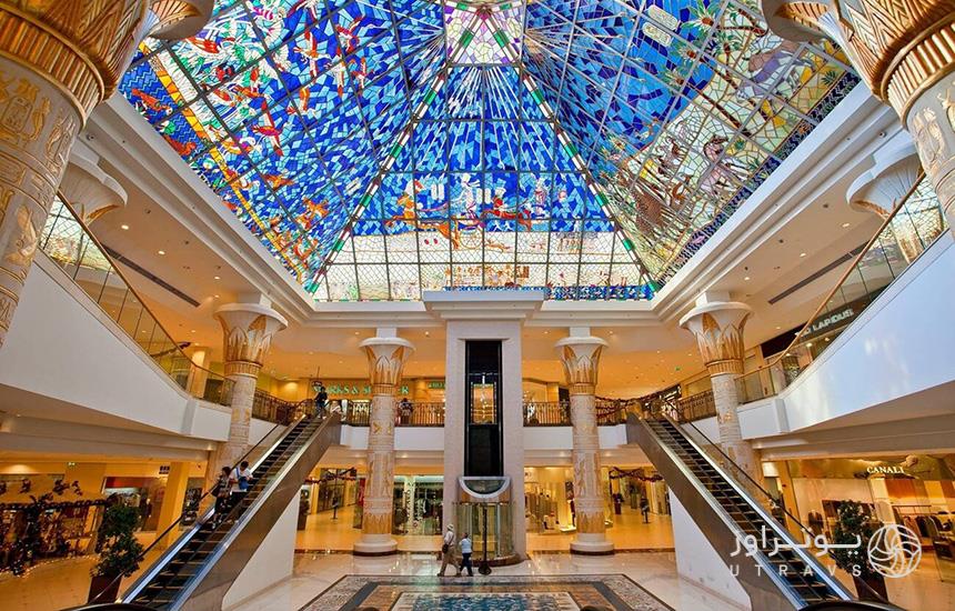 تصویری از فضای داخلی «وافی‌مال» دبی که سقفی تزیین‌شده با شیشه‌های رنگی و دو پله‌برقی در آن دیده می‌شود.